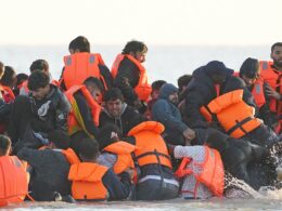 Migrant shouts ‘This is for Rishi Sunak’ as his inflatable boat leaves France towards the English Channel, stopping to collect more people at Calais in full view of French police