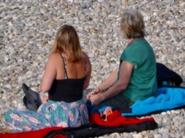 UK’s heatwave eases off but families flock to beaches to catch the day’s early sun as highs of milder 23C predicted